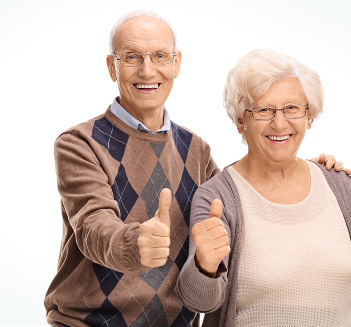 A smiling older couple giving a thumbs up.